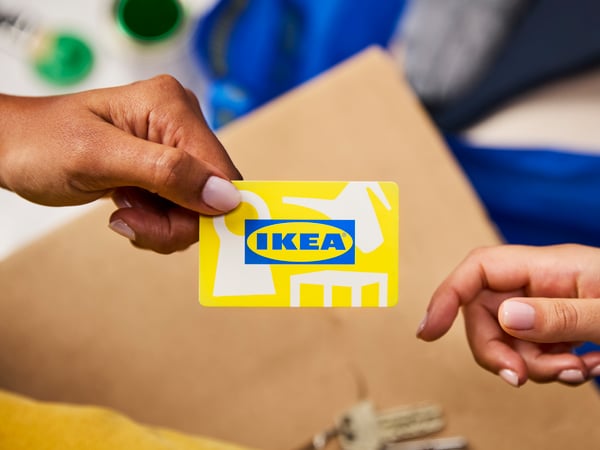 An IKEA gift card being passed from one hand to another.