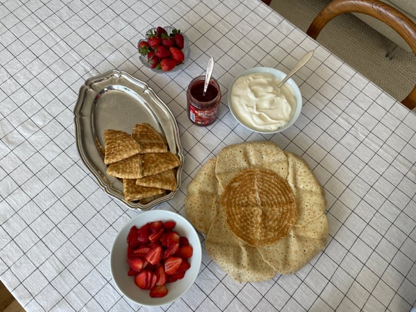 Bild tagen uppifrån på ingredienser till en pannkakstårta som är upplagt på ett bord med en rutig duk.