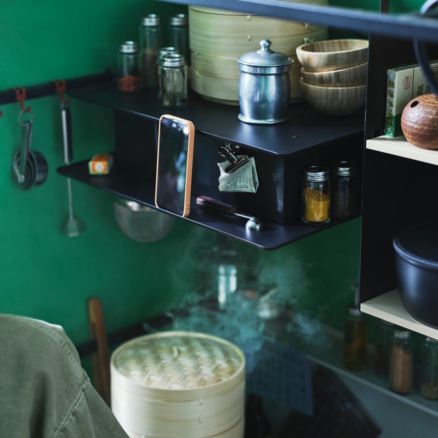 Steam is rising in a kitchenette and into a VIGGBO wall mounted extractor hood, with small bowls and jars sitting on it.