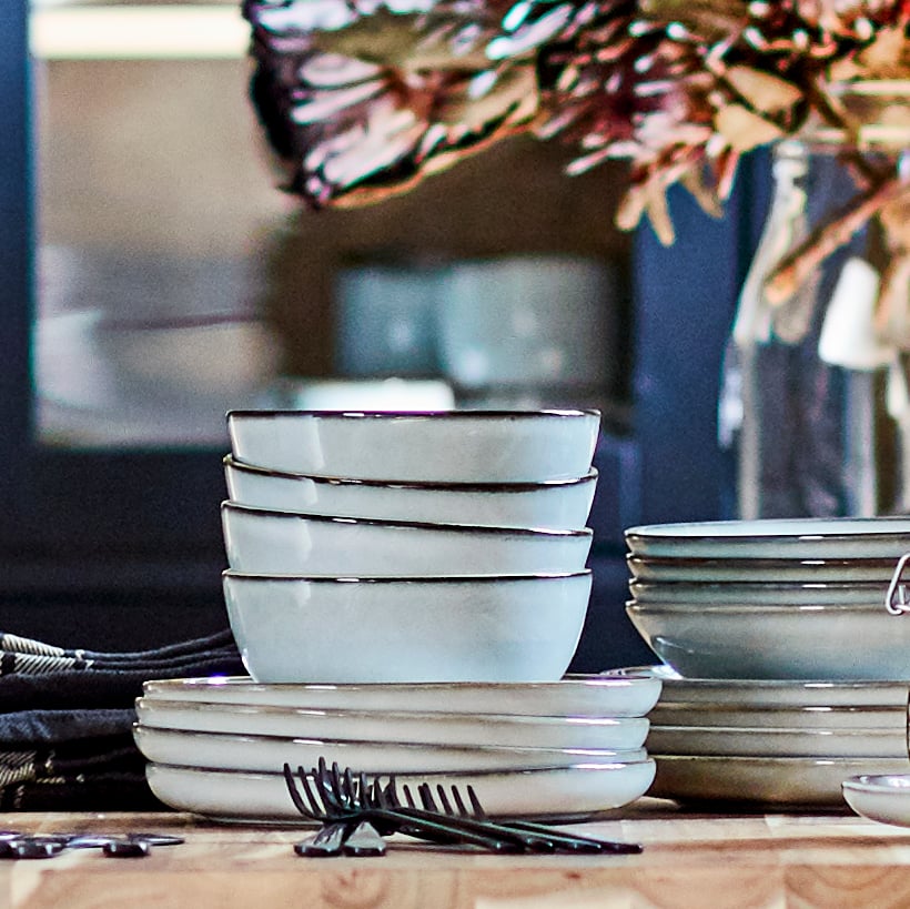 Una mesa con platos y pocillos GLADELIG arrumbados unos sobre otros.