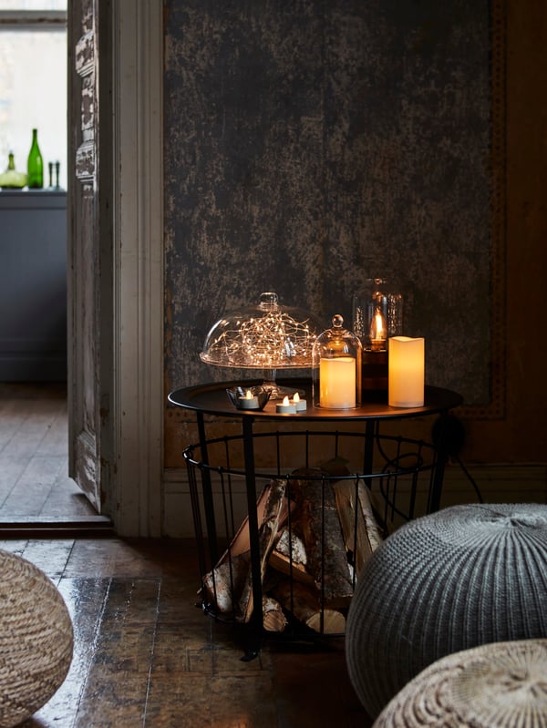 A living room corner with a LED light display, using LED candles, tealights, and a light chain under a glass dome.