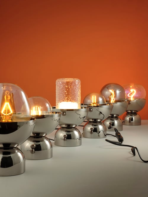 Spațiu de lucru cu mai multe lămpi de masă ACKJA amplasate pe o suprafață albă lângă un bec LED MOLNART cu tub e 27 150 lumeni.