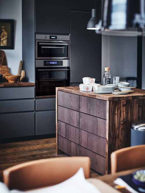 Kitchen with 2 base cabinets with 4 fronts, 2 low and 3 middle drawers made of wood, multiple bowls and a pendant lamp.