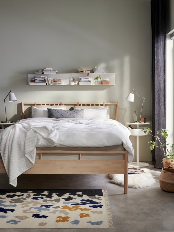 Une chambre à coucher avec un lit BJÖRKSNÄS en bouleau, une table de chevet blanche et un linge de lit.