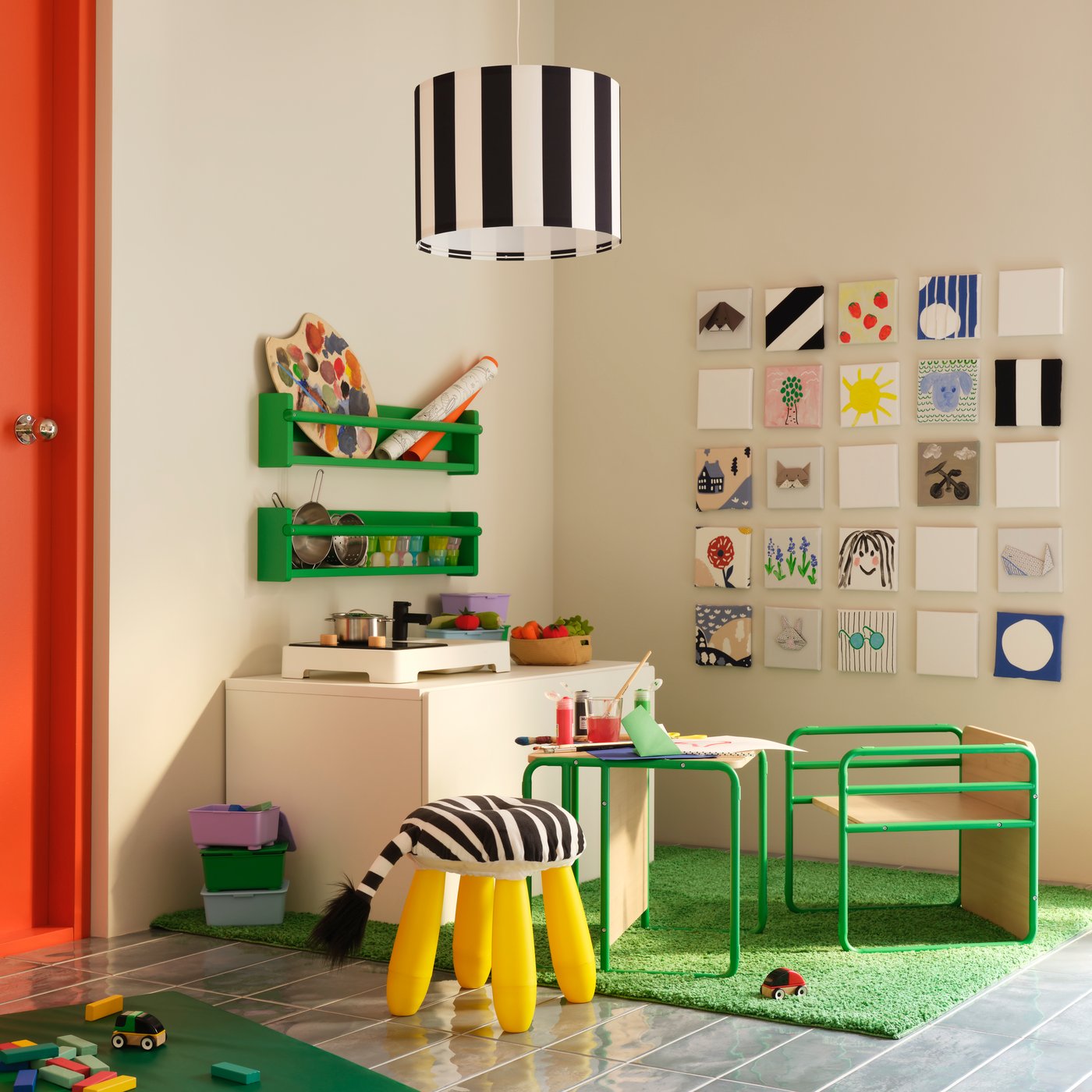 A corner with a green SMÅSKRAKE children’s chair-and-table alongside a STENMUS play kitchen and colourful drawings.