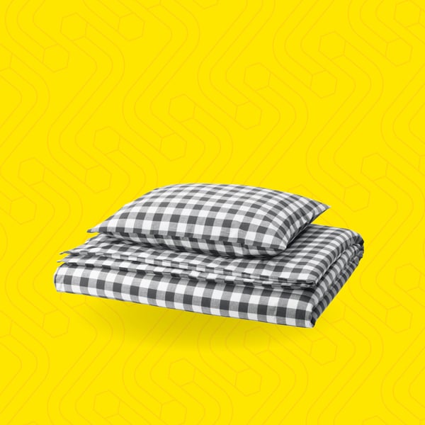 Svart og hvitrutet sengetøy på gul bakgrunn.