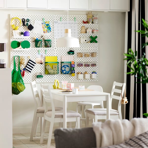 An off-white TONSTAD extendable table surrounded by four white chairs, set in a bright dining area with wall-mounted storage.