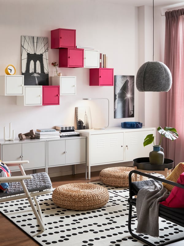 Una sala con un mueble para TV blanco y una alfombra. Sobre el tapete un apoyapié de fibra,