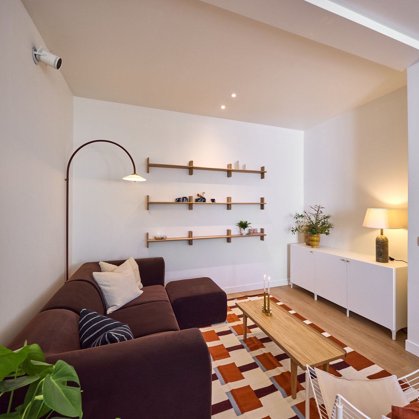 Gezellige woonkamer met hoekzetel, houten salontafel, wandplanken en warm licht, moderne en rustige inrichting.