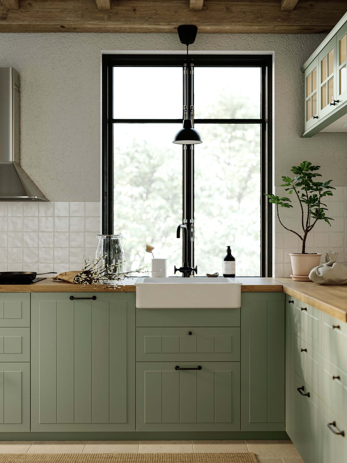 Cocina tradicional con ventanal luminoso, armarios bajos de color verde y encimera de laminado duradero de efecto roble natural.
