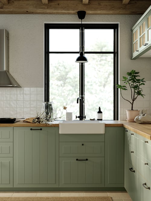Traditional kitchen with light large window, green base cabinets, and durable natural oak effect laminate worktop.