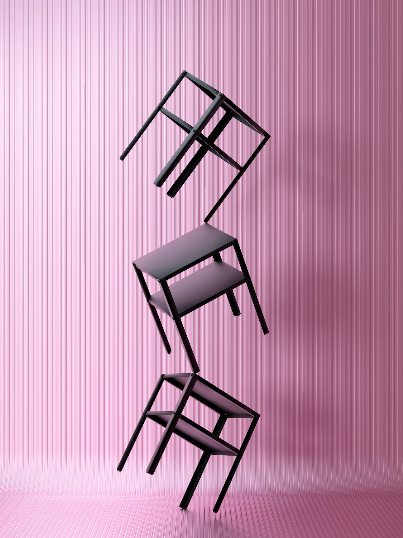 Trei noptiere KNARREVIK negre sunt așezate în echilibru una peste alta, într-un picior, în fața unui perete roz texturat.