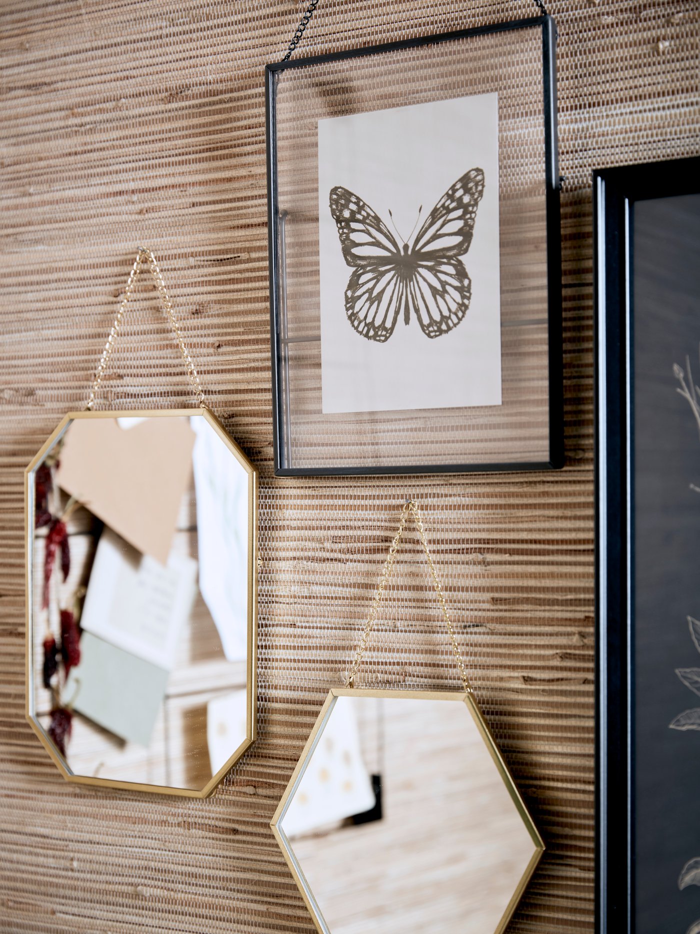 A hall with stone-coloured walls where jackets hang inside a HAUGA open wardrobe. An oval mirror is on the wall.