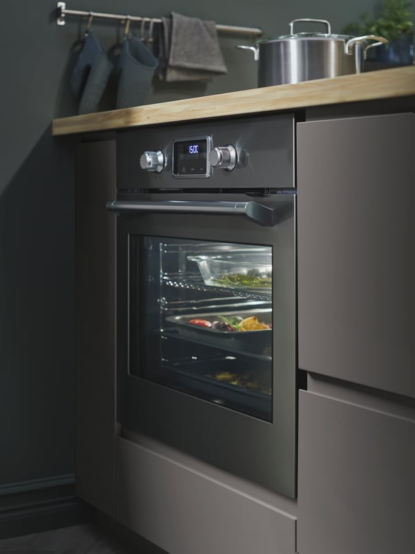 Stainless steel SMAKSAK oven in a kitchen with grey VOXTORP fronts
