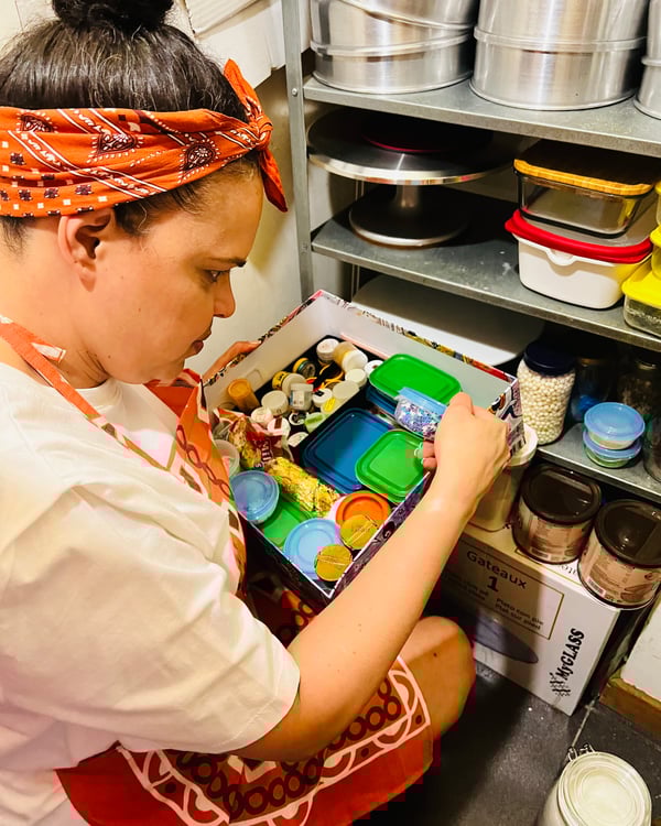 Blick von oben auf einen Holztisch mit Behältern voller Backzutaten wie Mehl, Zucker und Eiern. Außerdem sind Utensilien wie Teigschaber und ein Torten-Garnierset zu sehen.