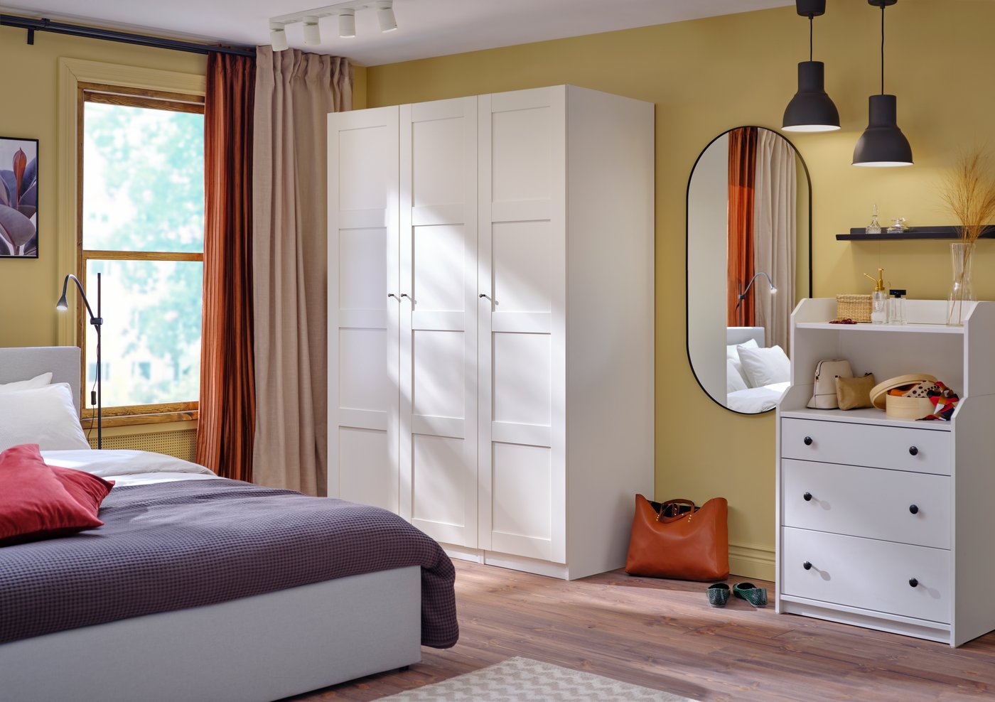 Ein weißer PAX Kleiderschrank in einem bunten Schlafzimmer.