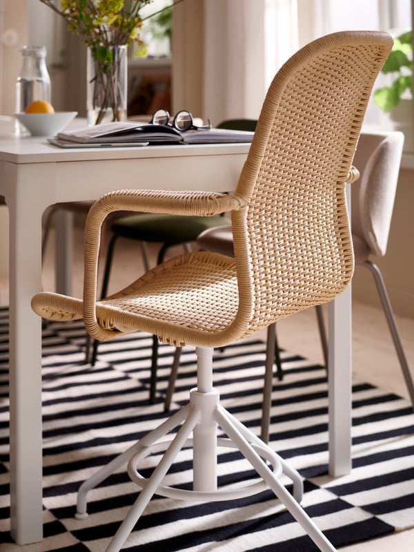 A STIGBYGEL swivel chair with armrests stands at one end of an EKEDALEN extendable table on a striped STOCKHOLM rug.