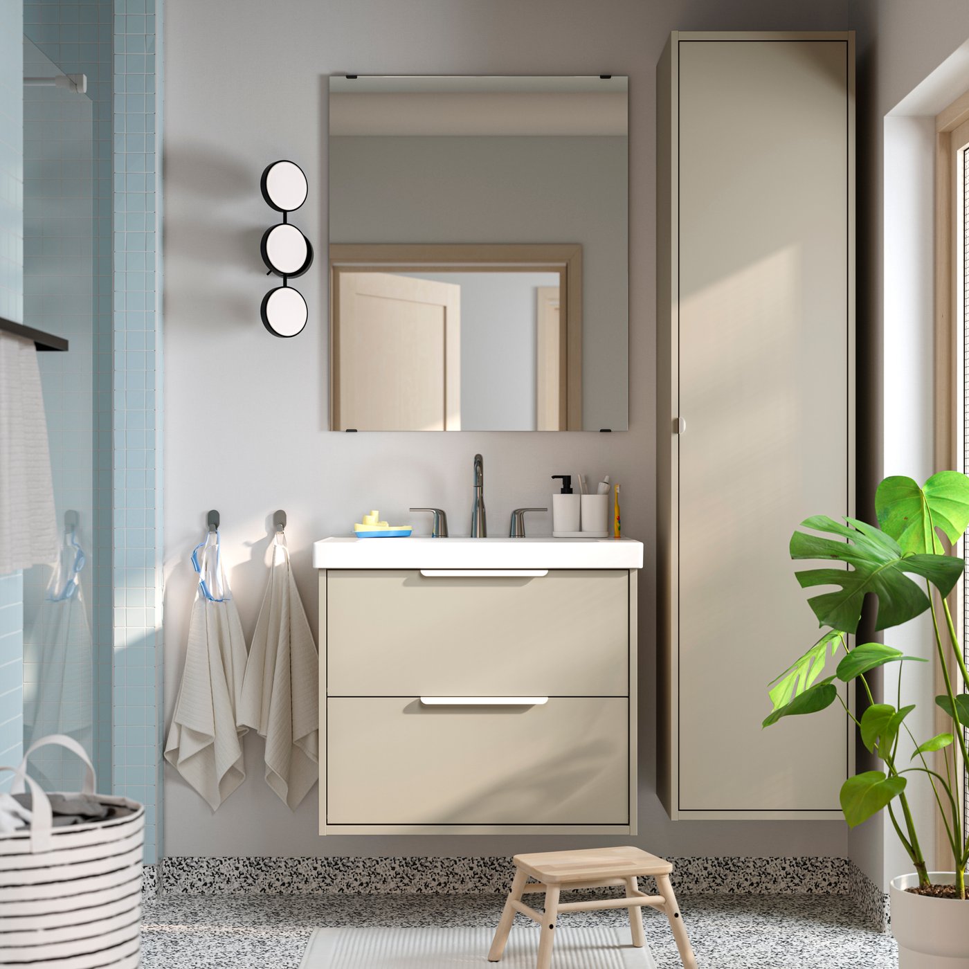 Béžová koupelna s velkým zrcadlem a květinou.