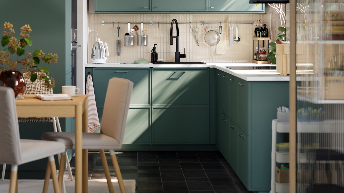 A small kitchen has base, wall and top cabinets, going all the way to the ceiling and there’s a small table with a chair.