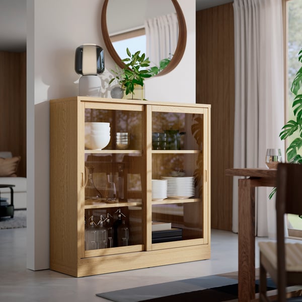 An oak veneer TONSTAD cabinet with sliding glass doors