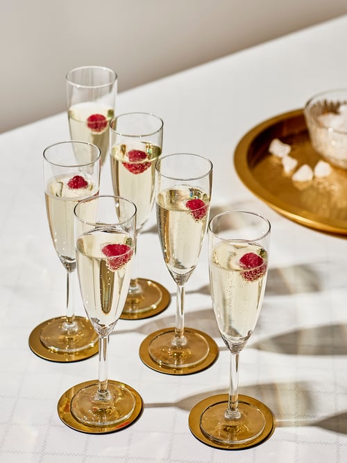 A modern dining room featuring a set of champagne glasses next to a golden tray with matching coasters.