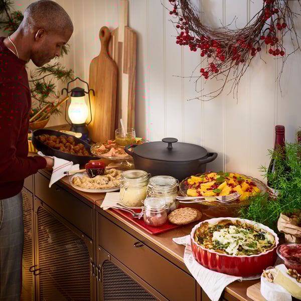 Buffet de Noël suédois avec boulettes de viande, harengs et autres aliments IKEA dans des ustensiles de service, dont une casserole VARDAGEN.