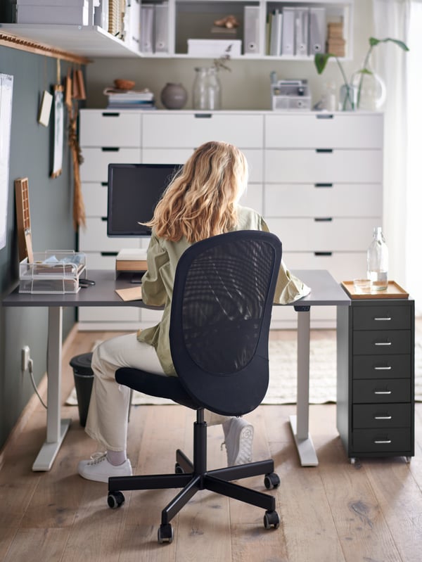 Schwarzer FLINTAN Drehstuhl in einem Büro, mit einer Dame, die auf dem Stuhl sitzt.