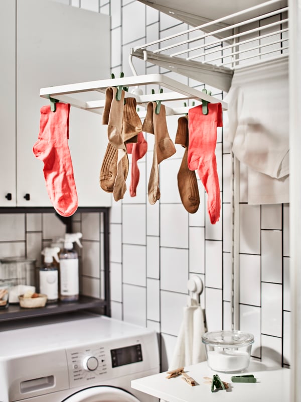 Plusieurs chaussettes colorées sont suspendues à un séchoir blanc.