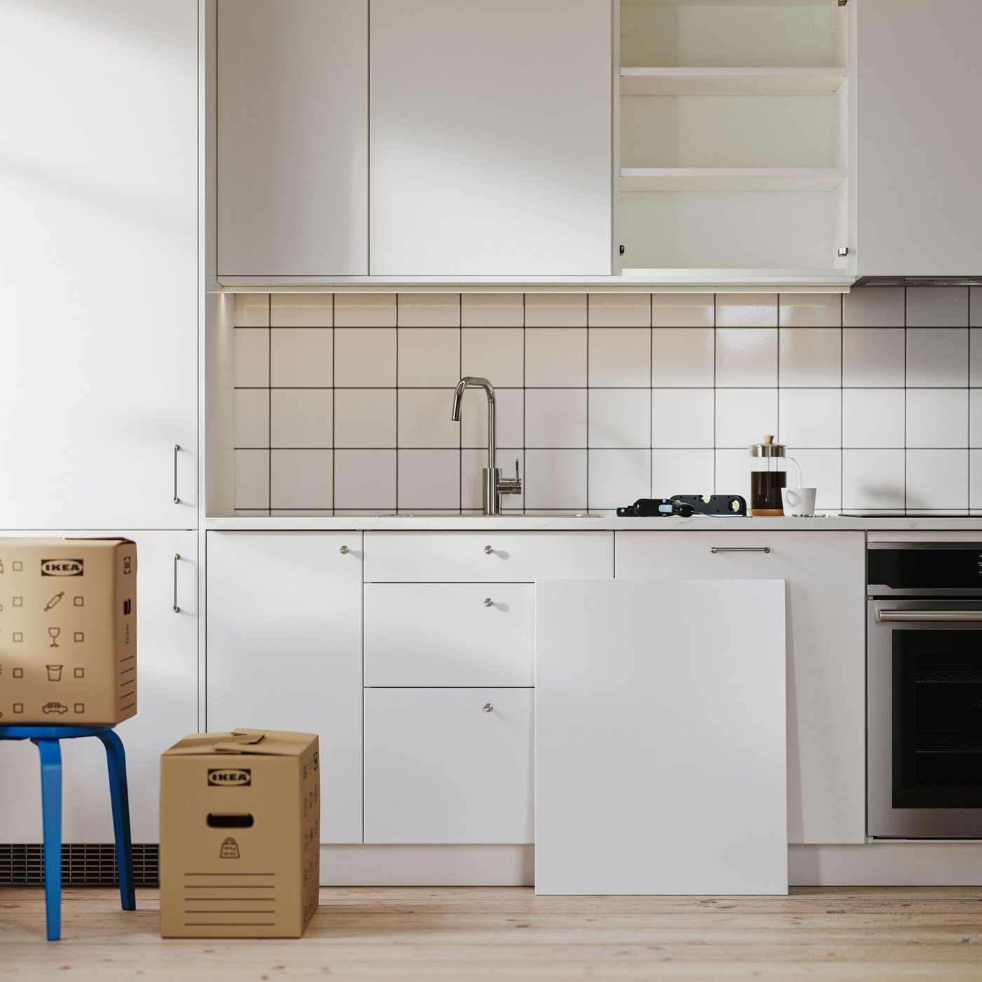 A white SEKTION kitchen in the last stages of installation. A drawer sits on the floor and its front leans against a cabinet.