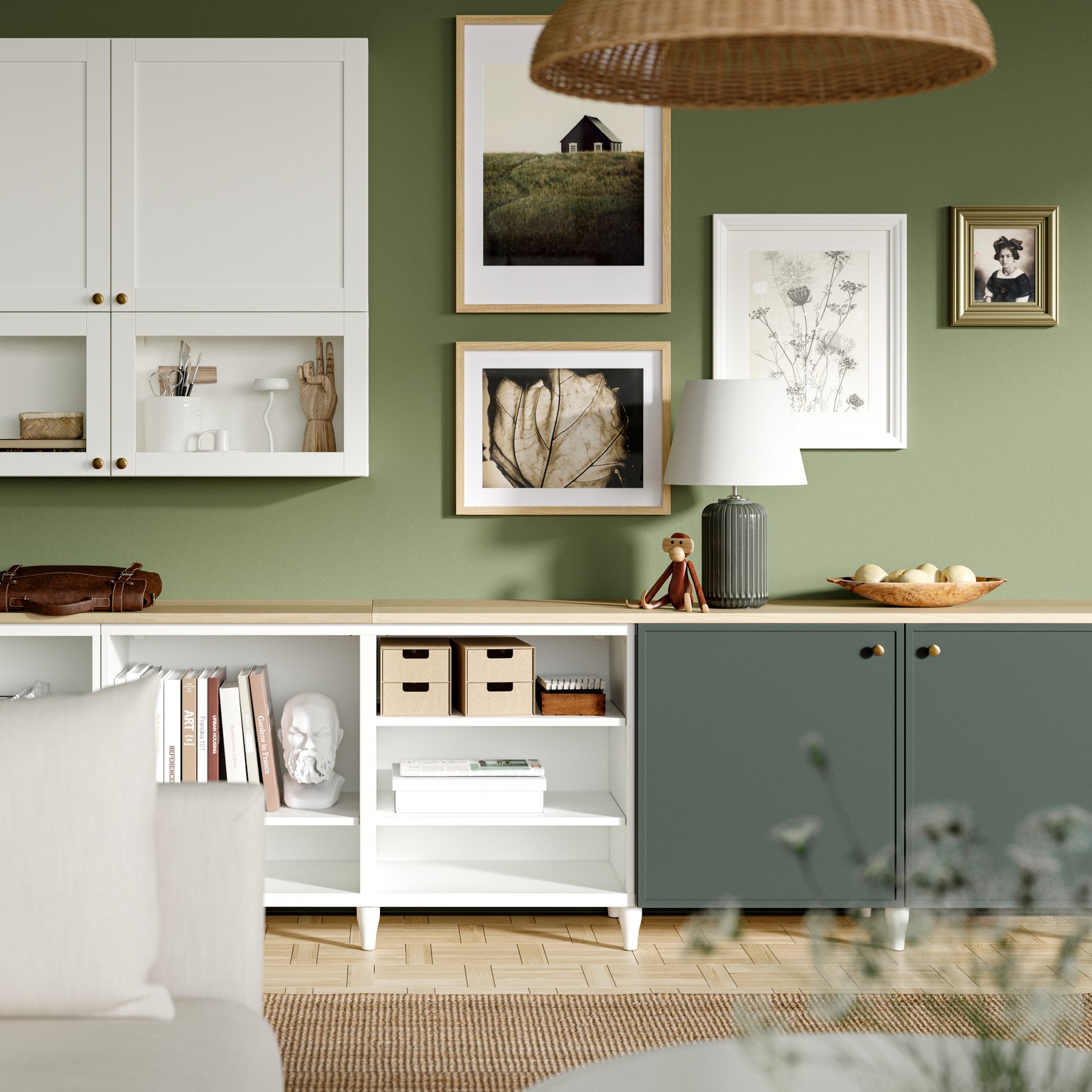 Three BESTÅ frames on legs in a living room with two oak veneer top panels on top. Green KRUKMAKARE fronts are on one frame.