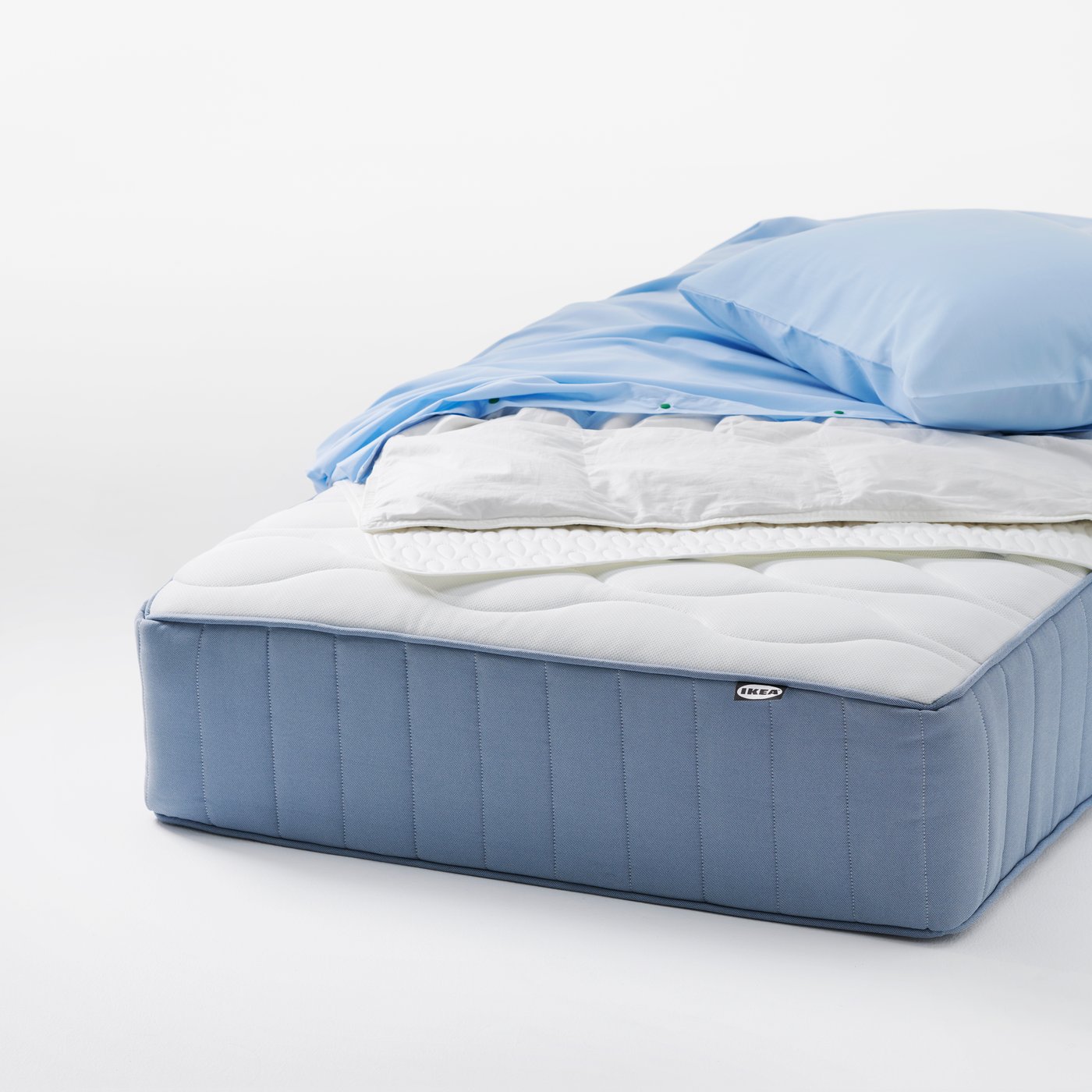 En obäddad VÅGSTRANDA resårmadrass med pocketfjädrar, med lätt sängkläder placerade ovanpå, i en ren studiomiljö.