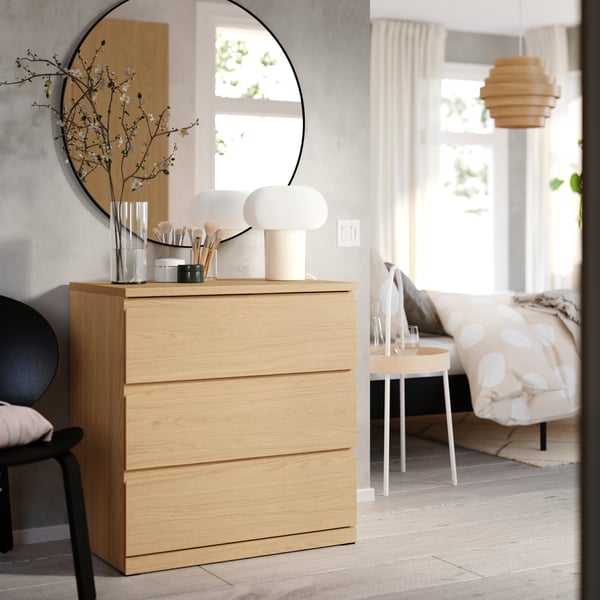 A STORKLINTA chest with 3 drawers in oak effect stands in a hallway outside a bedroom.