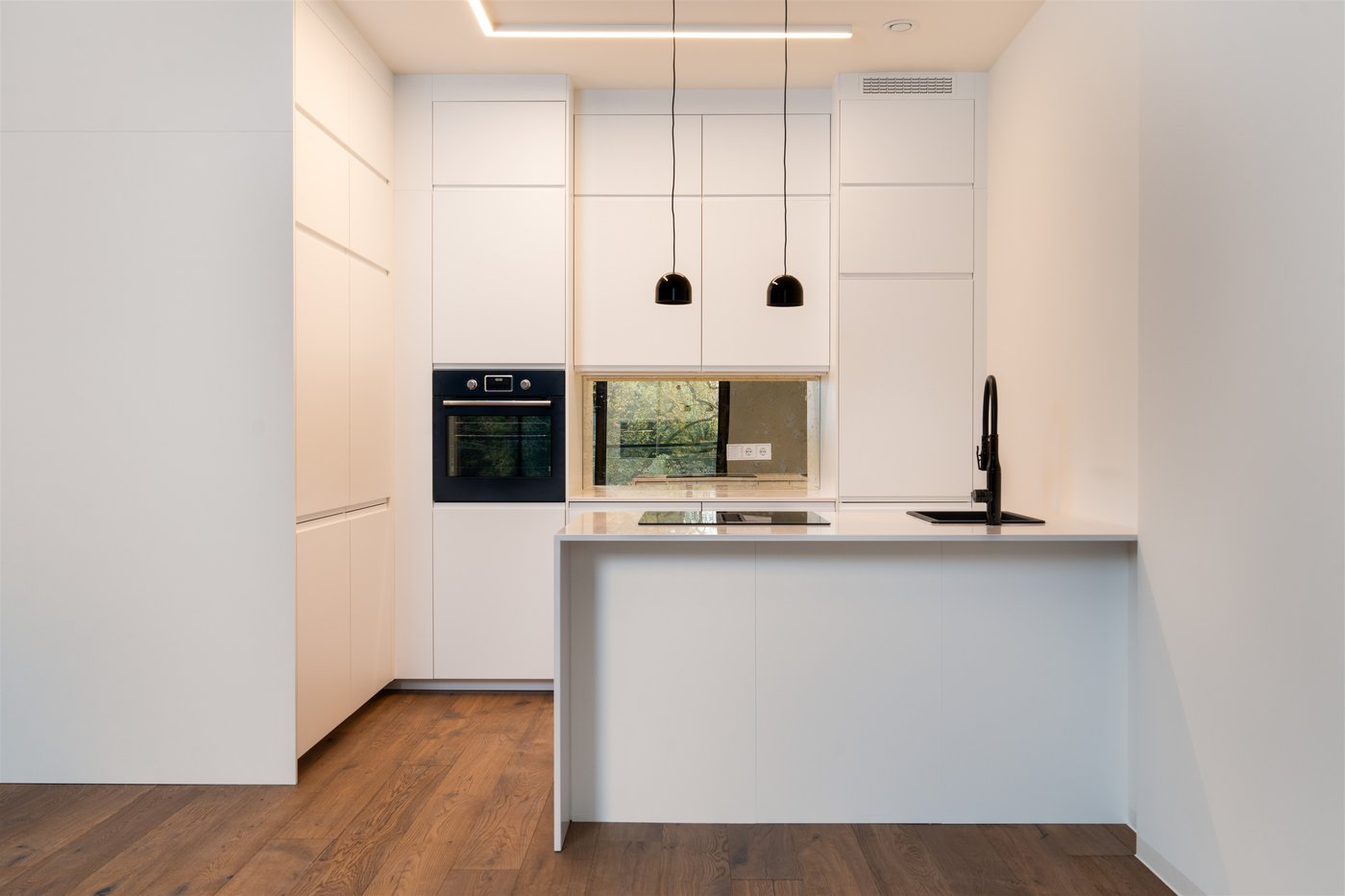 Auf dem Bild sieht man eine weiße Küche mit Kücheninsel.  