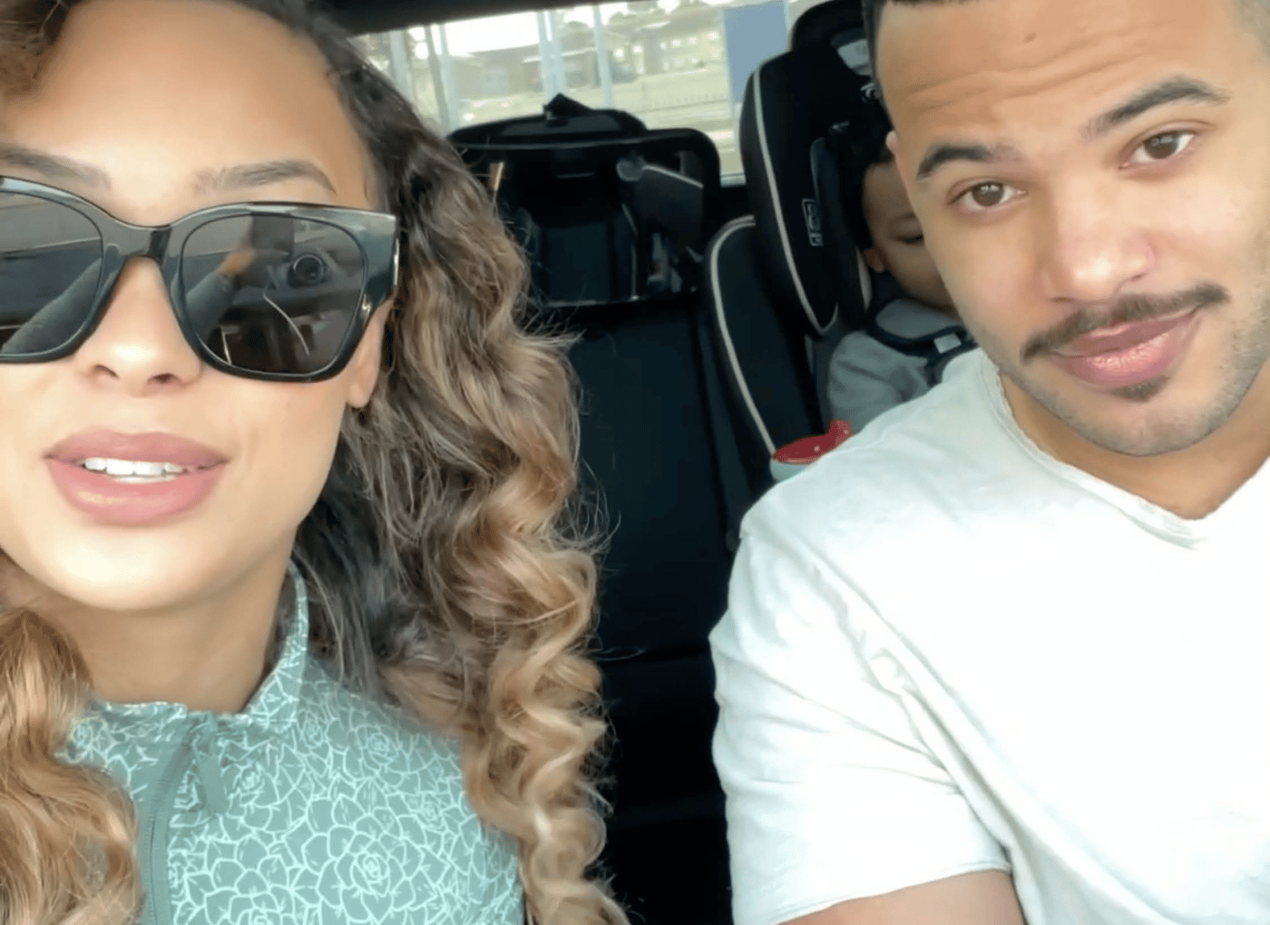 الوالد والوالدة في عائلة سكوت في سيارة، وهناك طفل في مقعد السيارة بالكاد يظهر في الخلفية.