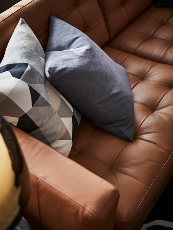 A grey and white pillow on a LANDSKRONA leather sofa