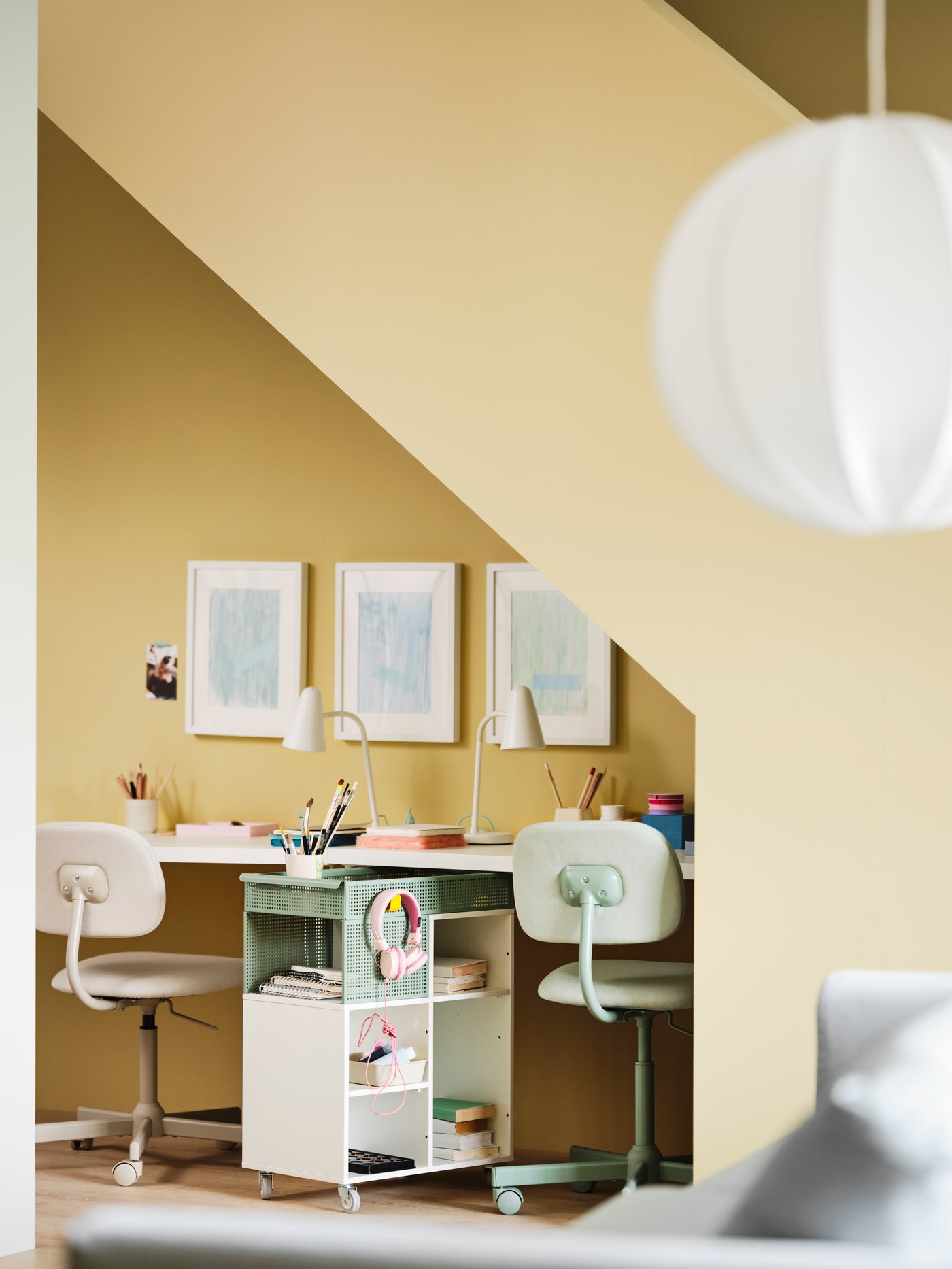 اثنان من كراسي BLECKBERGET الدوارة ومكاتب ومصابيح عمل وعربة ÖVNING يشكلون ركناً للمذاكرة أسفل السلم.