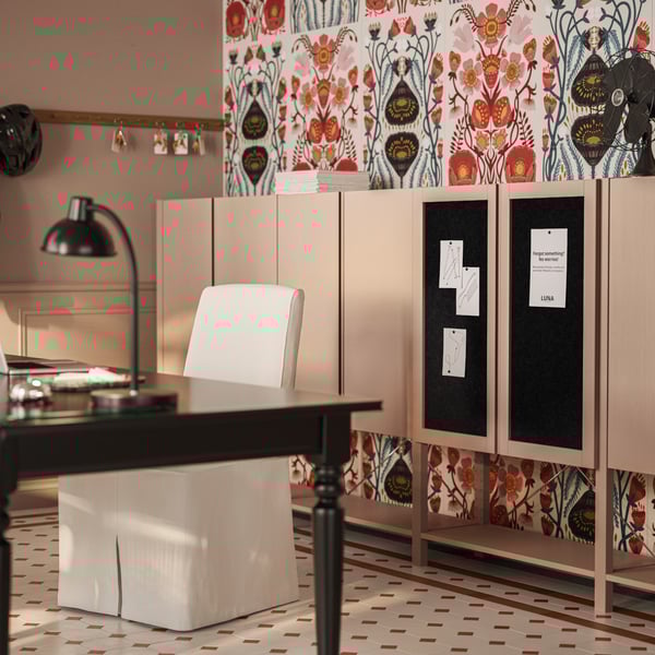 An IVAR shelving unit with pine/dark grey felt doors is between cabinets, behind a desk in a classic-styled reception area.