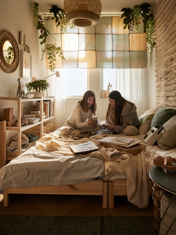 An off-white HUMLEMOTT throw on top of a pulled out UTTAKER bed in a Bohemian stye teenage room with earthy tones.
