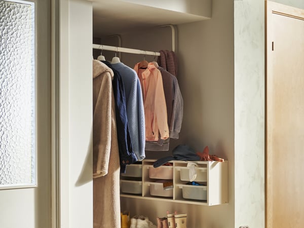 Colourful clothes on clothing rack in well-lit hallway with small organisers on wall.