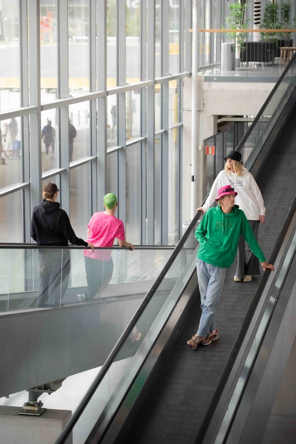 Fyra personer som åker upp och ner på rulltrappor och som har på sig IKEAs streetwear kollektion AURTIENDE.