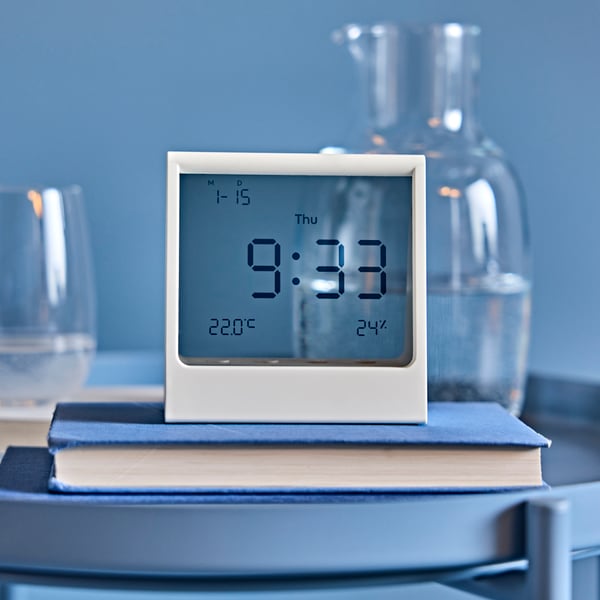 Reloj despertador RÖDBENA con termómetro e higrómetro integrado en un espacio del hogar.