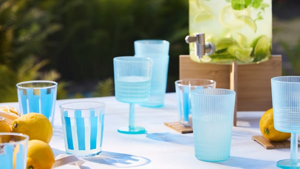 KALLSINNIG and PILLESTARR blue glasses on an outdoor table, along with an IKEA 365+ jar filled with lemonade.