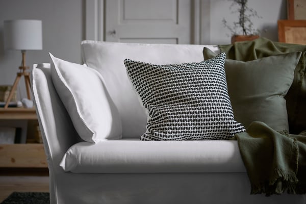 Vit soffa med prydnadskuddar med gråa kuddfodral. 