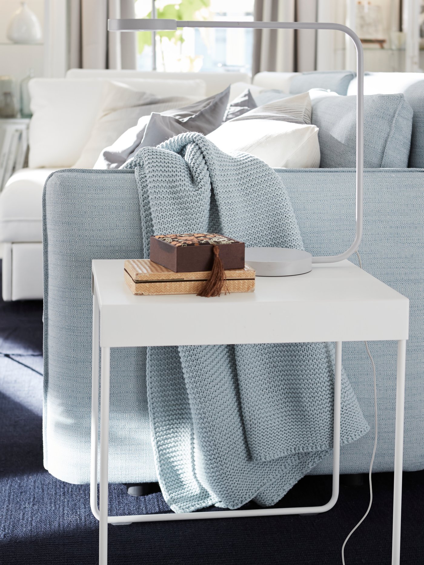 IKEA YPPERLIG white LED lamp on a white coffee table next to a VALLENTUNA sofa.