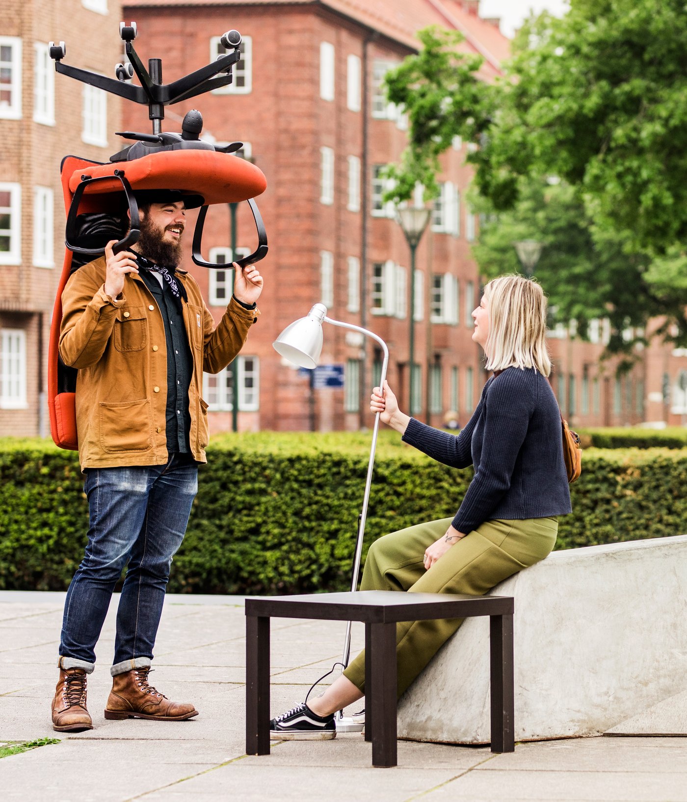 Two people are outside holding different pieces of furniture.