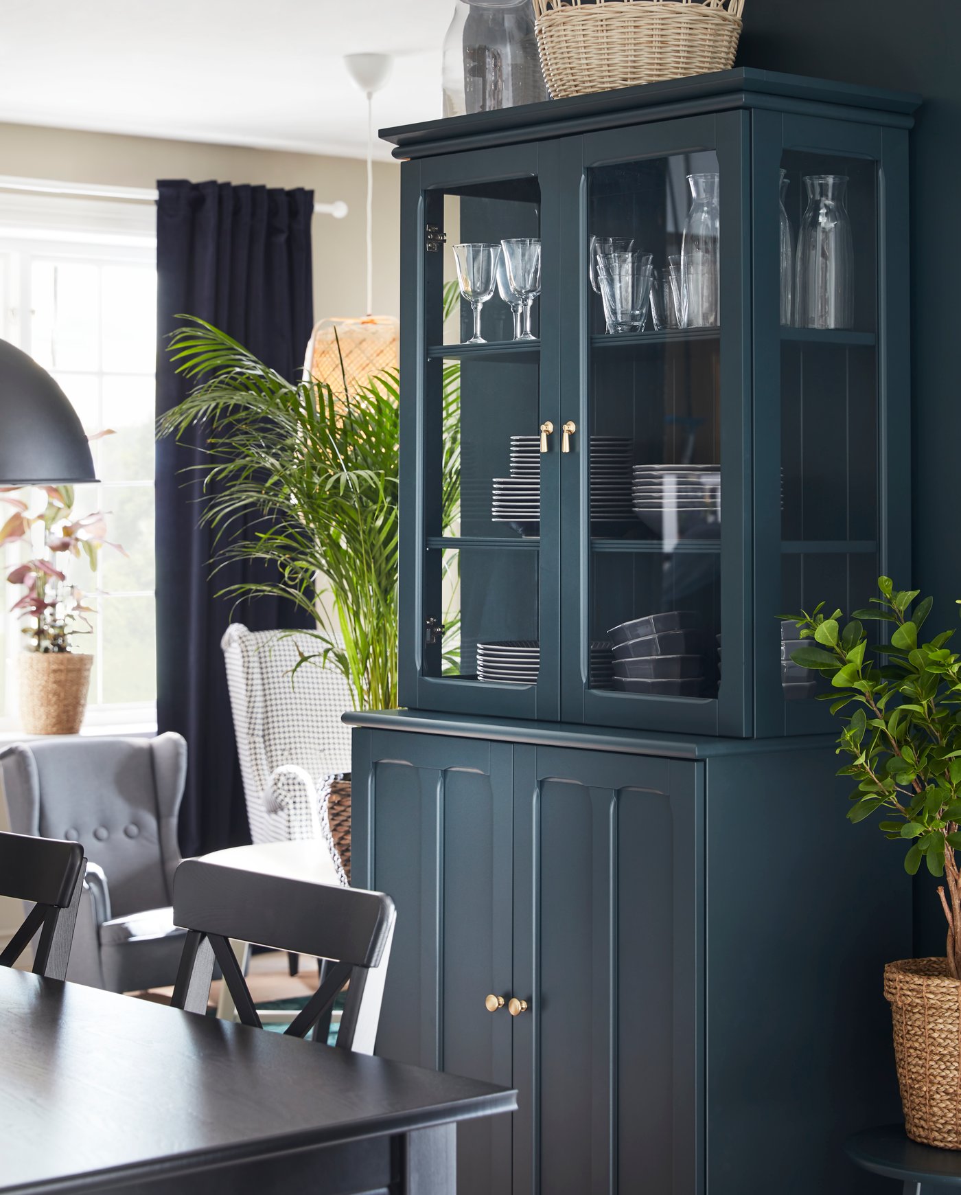 A dark blue-green LOMMARP cabinet with glass doors in the living room
