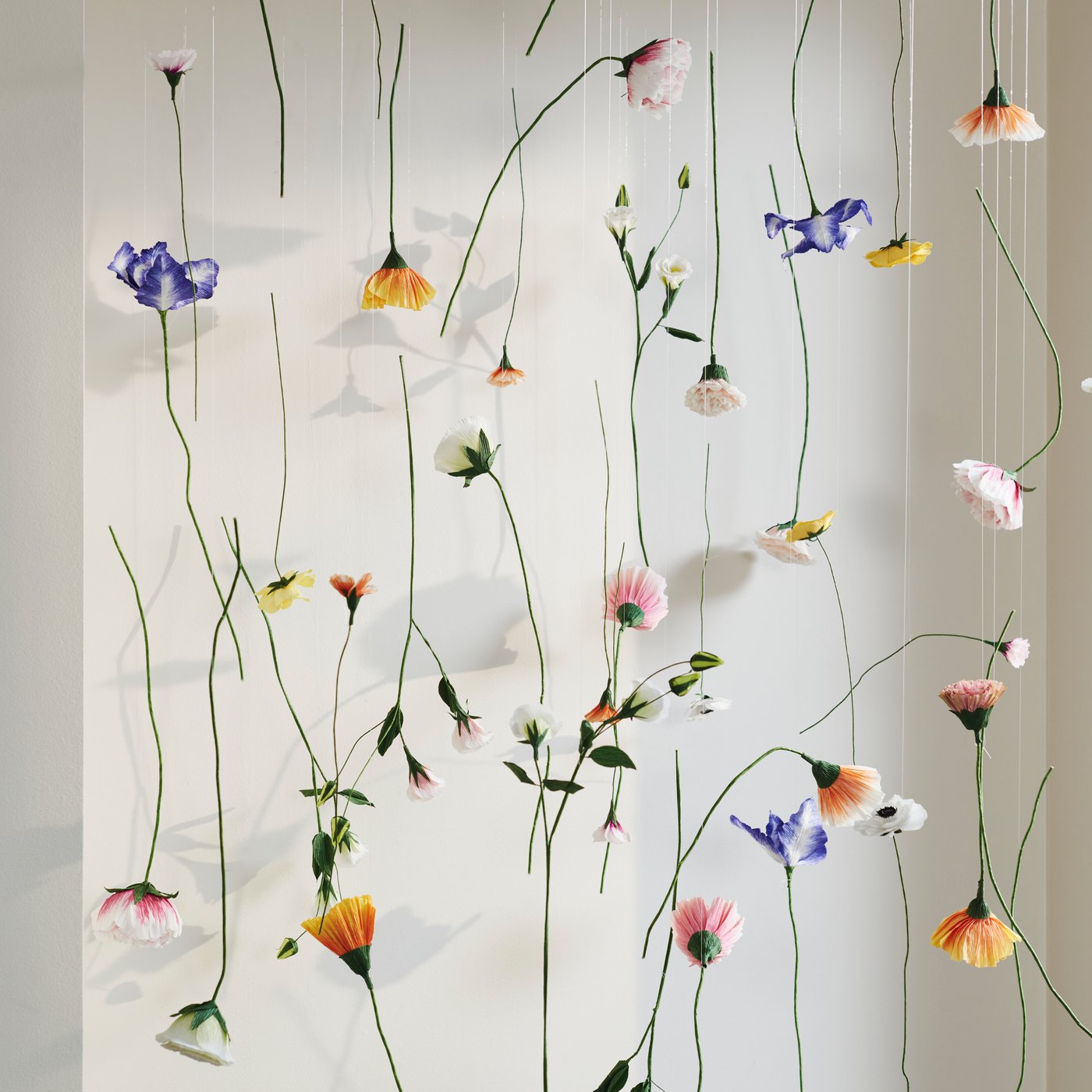 Flera GULDSPETT pappersblommor hänger från trådar i taket. 