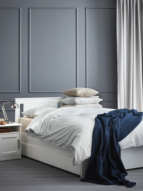 Bedroom with SONGESAND bed frame, SONGESAND bedside table, MAJGULL curtains, FORSÅ work lamp, INDIRA bedspread, and cushions.