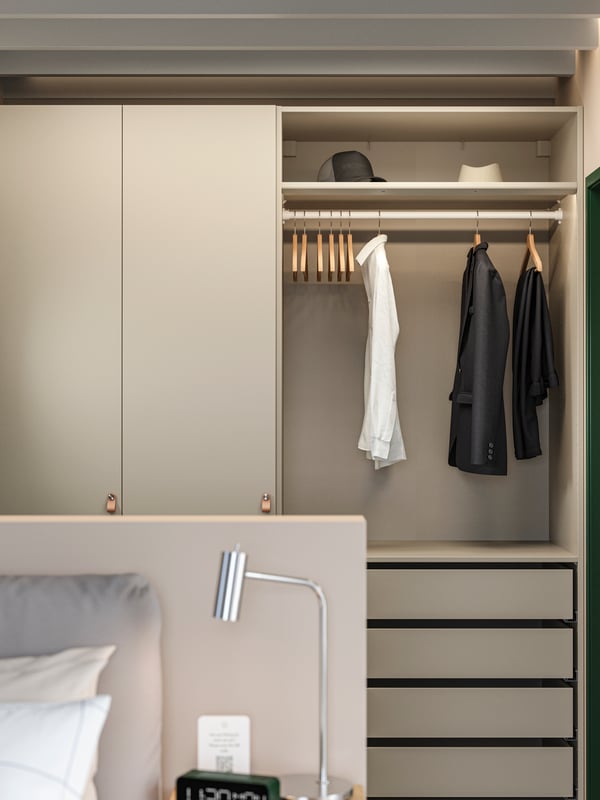 Een hotelkamer kamer met een PAX/FORSAND kledingkast met open en gesloten opbergruimte, een paar kleren, hoeden, hangers en lades.