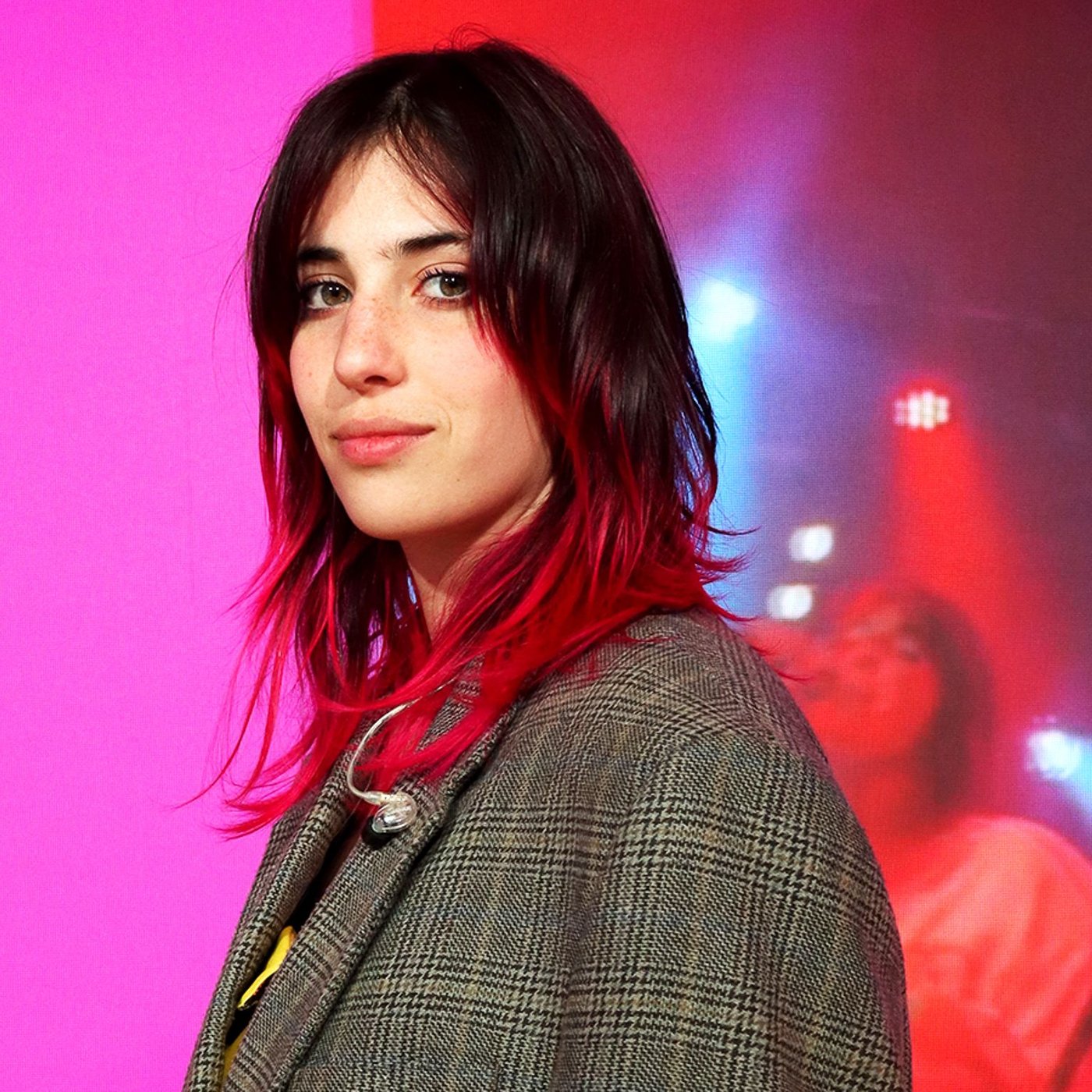 Während der Mailänder Designwoche 2024 steht Chiamamifaro am IKEA Standort auf einer Bühne. Im Hintergrund ist eine digitale Anzeige in Rosa zu sehen.